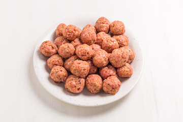 Raw meatballs on plate and white background