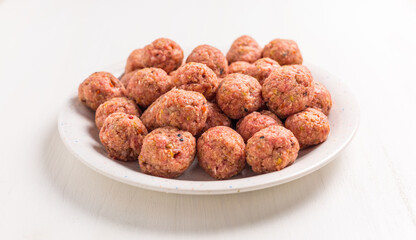 Raw meatballs on plate and white background