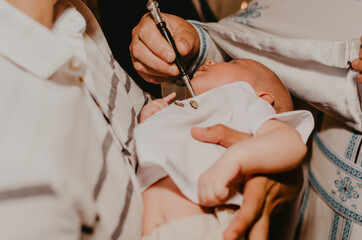 rite of sacrament of epiphany child baby in church. priest blesses child, smears with holy water,...
