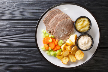 Boiled veal or Tafelspitz is the king of the beef dishes in Vienna close-up in a plate on the table. horizontal top view from above