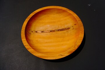 Unique wooden plate isolated on black background, homemade from Indonesia.