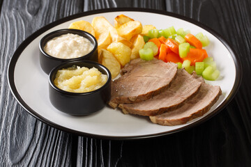 Tafelspitz Vienna's Favorite Cut of Boiled Beef with Traditional Accompaniments close-up in a plate on the table. horizontal