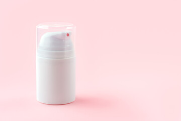 Mock-up concept. White cosmetic bottle with cream dispenser on pink background. Woman cosmetics concept. Skincare cosmetics. Pink monochrome. Cream jar. Front view.