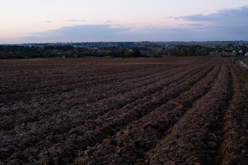 Freshly plowed black rich soil on a field in a sunset.