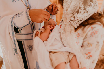 rite of sacrament of epiphany child baby in church. priest blesses child, smears with holy water,...