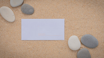 Arrière-plan grains de sable de mer, sable fin de plage avec enveloppe et galets. Emplacement pour texte sur papier.	