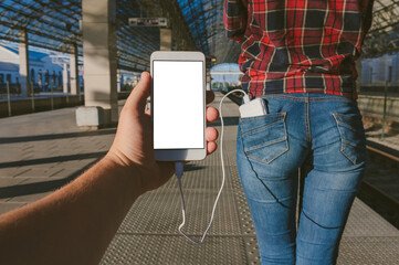 A mock-up of a Smartphone in the hands of a guy, stabs from the back pocket of a girl from a Power Bank against the background of the station.