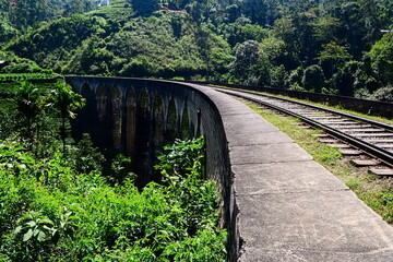 The Nine Arches Bridge in Demodara. Stone bridge in colonial style. Old railway arches bridge turning left in mountains. Ella, Sri Lanka.