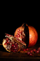 Open pomegranate with a quarter to the side and beads. Baroque style still life