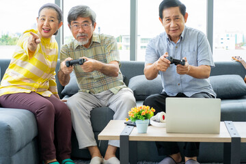 group of senior Asian people playing video games  at home for christmas and new year traditional festival party.