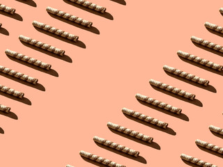 Wafer tubes diagonal pattern with sharp shadows on a cream background with copy space. Minimal sweet food concept