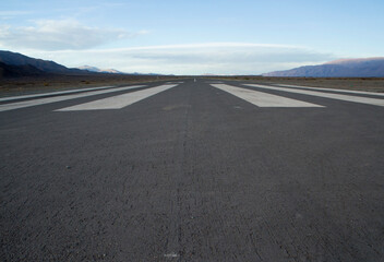 Transport. Wide straight asphalt airdrome road across the desert and into the mountains.