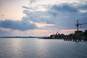 Fototapeta premium Seaport at sunset. Sea Bay and crane on the background of the sea and sunset