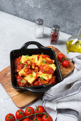 Homemade pasta ravioli with tomato ragu Bolognese on black pan on a wooden board. food delivery from restaurant to home. top view, pasta recipe  Italian cuisine.