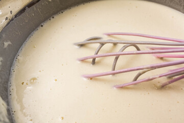 Manual whisk mixing cream and egg for cooking dessert