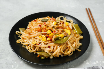 Noodles with vegetables in a black plate with soy sauce top view. home cooking recipes