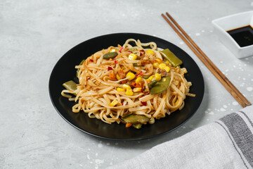 Noodles with vegetables in a black plate with soy sauce top view. home cooking recipes