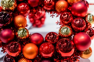 Holiday round frame, red and orange glass Christmas balls, isolated on blurred background.Happy new year decoration for home. Merry Christmas. Advent Christmas wreath