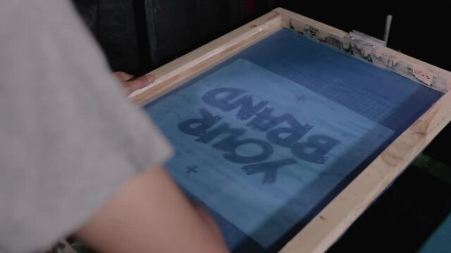 Man preparing silkscreen by hand for used to work printing t-shirts