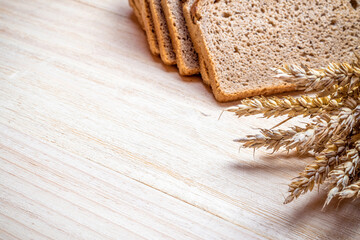 Rye bread isolated. Bakery with crusty loaves and crumbs. Fresh loaf of rustic traditional bread with wheat grain ear or spike plant on natural wooden background. Bio ingredients, healthy with seeds.