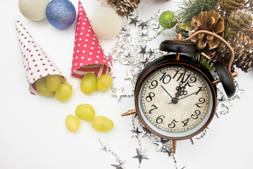 Paper cone for New Year's Eve grapes, next to the clock about to strike midnight.Pineapples, Christmas balls and silver star garland decoration.