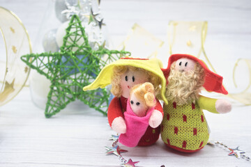 Cloth dolls of St. Joseph, Mary and the baby Jesús the background a green star and a golden garland.