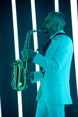 Side view saxophone player in a white suit against the backdrop of neon lamps with blue backlight....