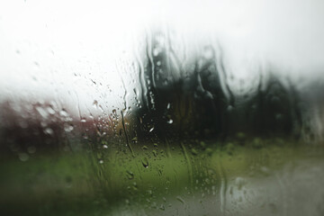 Shallow depth of field (selective focus) image with water pouring down outside a car window during a rainy day.