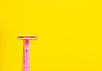 The concept of hair removal, sugaring, wax. Beauty salon, Spa treatments. Shaving vs hair removal. Sugar depilatory paste runs down a pink razor on a yellow background. Copyspace.