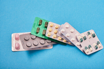 pile of pills in blister packs on blue background