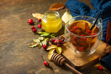 Healthy winter vitamin drink. Hot rosehip tea with honey and dried fruits on a wooden table top. Copy space.