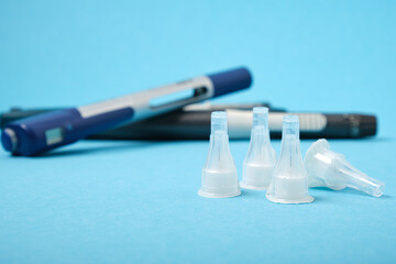 assorted syringe pens for insulin injection and new sterile injection needles, blue background