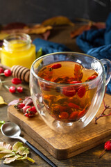 Healthy winter vitamin drink. Hot rosehip tea with honey and dried fruits on a wooden table top.