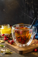 Healthy winter vitamin drink. Hot rosehip tea with honey and dried fruits on a wooden table top. Copy space.