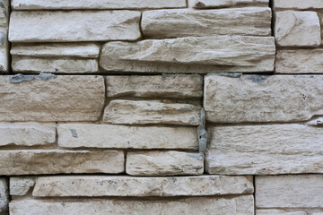 Clay sandstone gray bricks. Wall with protruding layered stone blocks. stone structure pattern