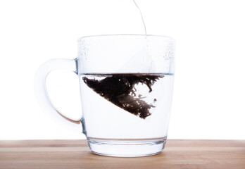 brewed a bag of black tea in a transparent mug on a wooden table.