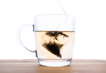 brewed a bag of black tea in a transparent mug on a wooden table.