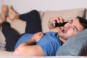 Shocked man using phone in sofa