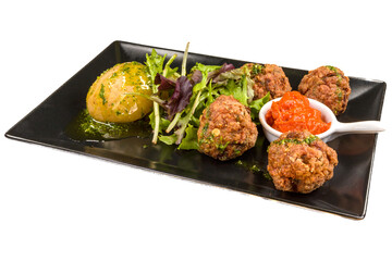 Delicious fried meatballs with arugula, potatoes and tomato Ljutenica. on black plate,