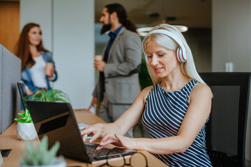 Attractive business woman in the headphones using laptop