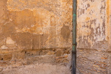 Aging cement and brick walls with yellow, burnt umber, saffron, sand paint peeling off coatings outdoors on a shabby background. in Italy  open teal water pipe Vintage Antique