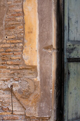 Aging cement and brick walls with yellow, burnt umber, saffron, sand paint peeling off coatings outdoors on a shabby background. in Italy  open door teal Vintage Antique