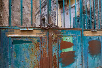 Old flaking paint on rusty door, rust, blue, green, orange, teal, turquoise in graphic patterns, frames and lines 