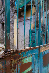 Old flaking paint on rusty door, rust, blue, green, orange, teal, turquoise in graphic patterns, frames and lines 