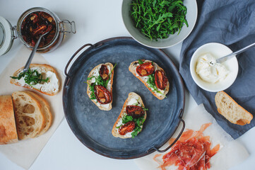 italian traditional bruschetta - bread toast with sun dried tomatoes, cream cheese, olive oil and arugula.