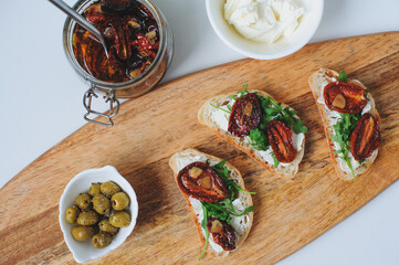 italian traditional bruschetta - bread toast with sun dried tomatoes, cream cheese, olive oil and arugula.