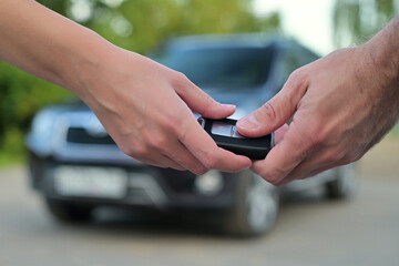 Woman and man pass the key to each other on the background of the car