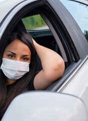 Girl wearing covid coronavirus mask in her car and touch her head