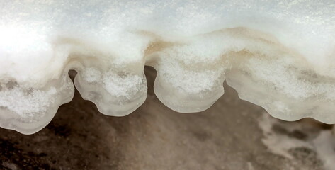 Icicles and frost on a snow-covered frozen river