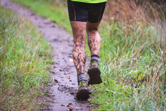 Athlete Runner In Forest Trail In Rain, With Muddy Legs